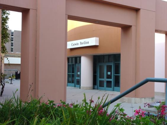 The entrance to Corwin Pavilion, framed by peach-colored arches, with greenery and pink flowers in the foreground.